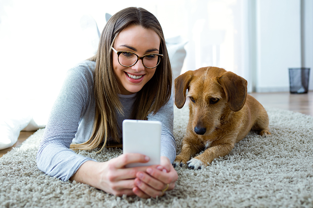 woman smiling with dog on phone image